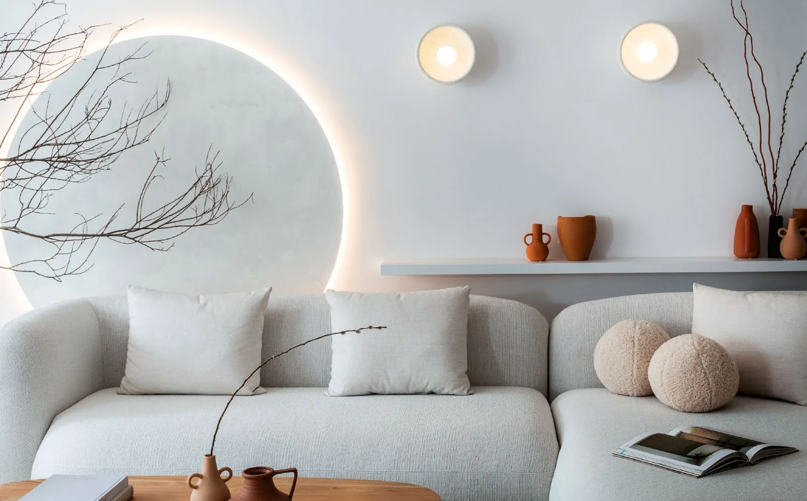 Living room with a backlit circular wall panel, two wall lights and a curved ivory sofa