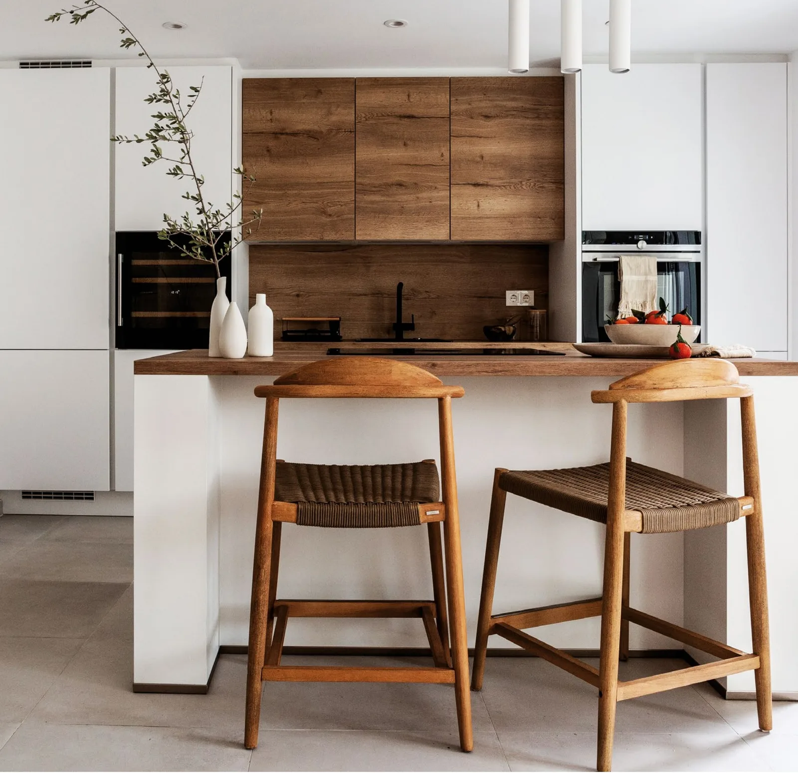 Kitchen island with two timber stools and warm wood wall units