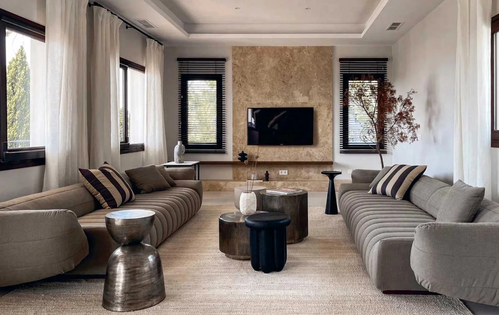 Living room with two long channel-tufted sofas facing each other and a stone feature wall