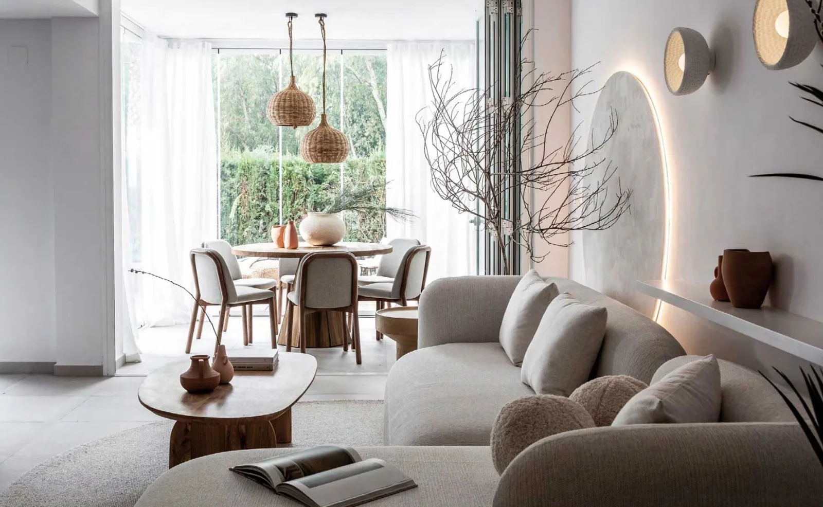 Living area with a curved sofa, round dining table and woven pendant lamps